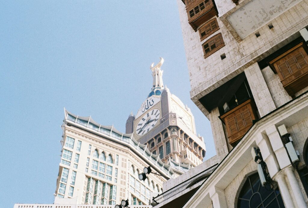 A dramatic view of Abraj Al Bait Towers with intricate architecture against the clear sky in Mecca, Saudi Arabia.